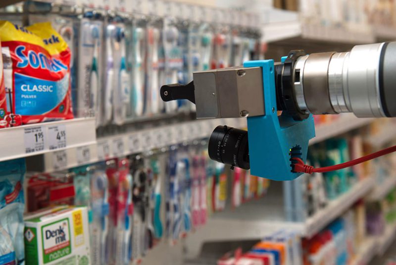 A robotic arm in front of a supermarket shelf